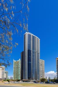 a tall building with trees and a sky background at Rhapsody Resort - Official in Gold Coast