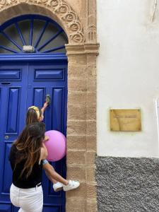 eine Frau mit einem rosa Ballon vor einer blauen Tür in der Unterkunft Riad le Consulat - Private Riad, Breakfast included in Essaouira