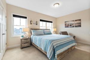 a bedroom with a bed and a chair and two windows at Sunset Sanctuary Steps to Beach Marsh Views in Hampton