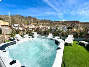 a hot tub on a lawn with chairs and mountains at Apartamento Naranja in Bolnuevo