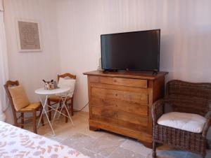 a bedroom with a television on a dresser with a table at L'oustau des balmes in Beaumes-de-Venise