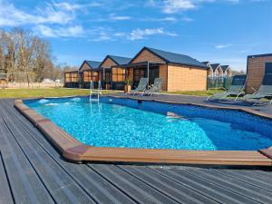 a swimming pool with chairs and a house at Domki RELAXO Rewal - domki nad morzem z podgrzewanym basenem, placem zabaw i strefą relaksu in Rewal