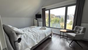 ein Schlafzimmer mit einem Bett und einem Stuhl und einem Fenster in der Unterkunft Ostsee - Reetdachhaus Nr 42 "Waterkant" im Strand Resort in Heiligenhafen