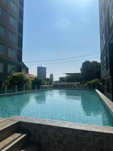 a swimming pool in the middle of two buildings at Modern Condo - BTS Bang Chak - Pool, Gym, Wi-Fi in Amphoe Phra Khanong