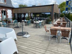 a patio with tables and chairs on a deck at Mobil Home récent en Camping 5 étoiles sur la côte de Normandie plage 1400 m in Houlgate
