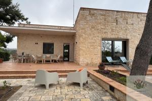 a brick house with a patio and white chairs at Villa Rossi in Polignano a Mare
