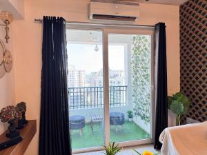 a bedroom with a sliding glass door with a balcony at Harmony Heights By Royal Rooms in Noida