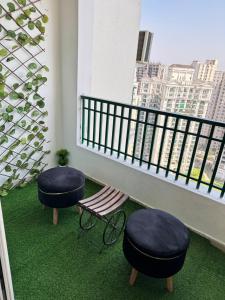 a balcony with two stools and a bench and a window at Harmony Heights By Royal Rooms in Noida