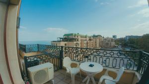 einen Balkon mit einem Tisch und Stühlen sowie einige Gebäude in der Unterkunft GoldenSands Apartments in Goldstrand