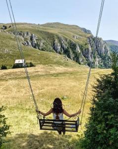 a person sitting on a swing in a field at Alpin Wellness & Spa Vlašić in Vlasic