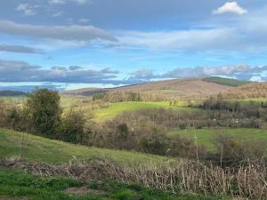a green field with hills in the distance at Down under in France in Lormes