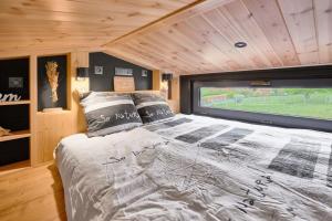 ein großes Bett in einem Zimmer mit einem großen Fenster in der Unterkunft Tiny BlackandWood in Redu