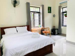 a bedroom with a large white bed with a chair at Bao Ky Homestay in Nguyên Ngoại
