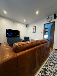 a brown leather couch in a living room with a tv at Logis Hotel de la Gare in Saint-Mihiel