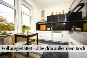 a kitchen with white cabinets and a black table at Großzügige 80m2 Gründerzeit FEWO mit privatem Parkplatz, Kingsize Betten, Nobilia Küche, 45 Zoll Smart-TV, 150Mbts WLAN - Nur eine kurzer Spaziergang durch den Park Venedig zur Krämerbrücke - Ausgewählte Empfehlungen für Erfurt inklusive in Erfurt