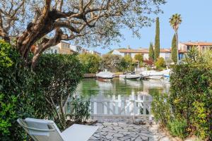 a white fence next to a body of water with boats at Une Maison Plein D Options YourHostHelper in Grimaud
