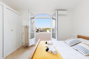 a bedroom with a white bed with a large window at Une Maison Plein D Options YourHostHelper in Grimaud