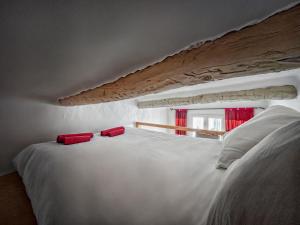 a white bed with two red pillows on top of it at T2 charmant avec mezzanine au cœur d'Aix in Aix-en-Provence +10 photos