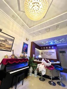 una stanza con un pianoforte, degli sgabelli e un lampadario di Dang Uyen 1 Hotel a Da Lat