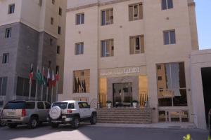 two vehicles parked in front of a building at Dahlia Hotel Apartment Riggae in Kuwait