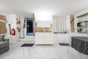 a kitchen with white cabinets and a living room at Family JC in Cagliari