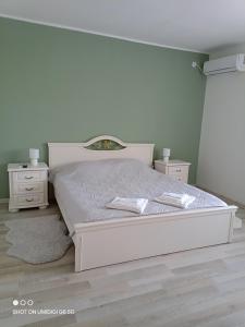 a bedroom with a white bed and two night stands at Къща за гости НИКА in Kavarna