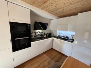 a kitchen with white cabinets and black appliances at Evolène Panorama- Renovated Apartment with Dent Blanche View 2-4 persons in Evolène
