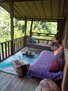 a porch with two beds and a couch on a deck at Ubud Jungle River in Ubud