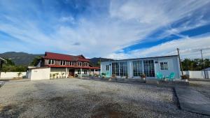a building with a red roof and two blue chairs at LumaYan, Guesthouse and Cabin in Yan