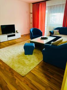 a living room with a couch and a table and blue chairs at El&Ma Apartment - 3 bedroom apartment with balcony close to Sarajevo City Center, Sunnyland - free parking in Sarajevo +9 photos