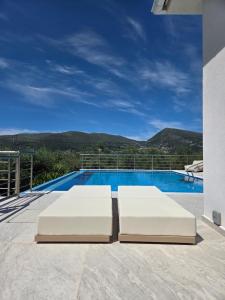 two white beds on a patio with a swimming pool at Villa Símera in Laganas