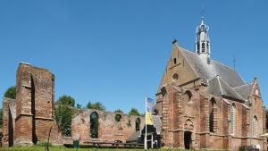 a large brick church with a tower and a steeple at Meerpaal 43 Bergen in Bergen