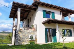 a white house with green windows and a balcony at Apartma Lavanda in Kojsko