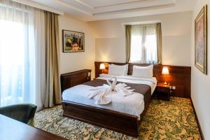 una camera d'albergo con un letto con un fiocco sopra di Hotel & Spa PALIĆ RESORT a Palić