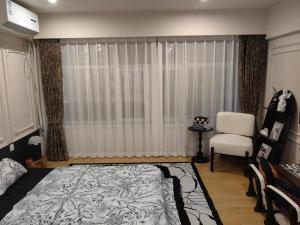 a bedroom with a bed and a chair and a window at Rooftop B&B in Harbin