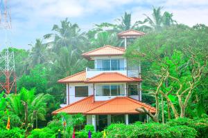 un edificio con tetto arancione in cima agli alberi di Janapriya Lake Resort a Polonnaruwa Altre 16 foto