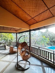 a balcony with a chair and an umbrella at Tropical Pool Villa Langkawi in Pantai Cenang