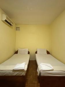 two beds in a small room with white sheets at SUNTIPHAB Guest House in Pakse