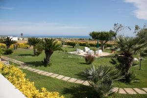 a garden with palm trees and chairs and the ocean at casa vacanze Gina in Marina di Pescoluse +2 photos