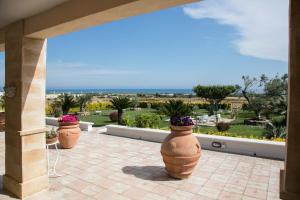 three large pots with flowers in them on a patio at casa vacanze Gina in Marina di Pescoluse