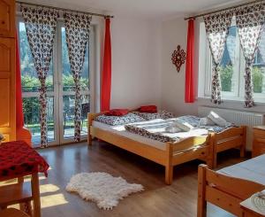 a bedroom with two beds and windows with red curtains at Kamila in Szczawnica