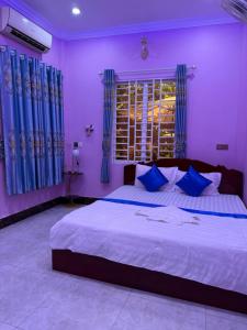 a bedroom with a large bed with purple walls and blue curtains at Bun Homestay in Battambang