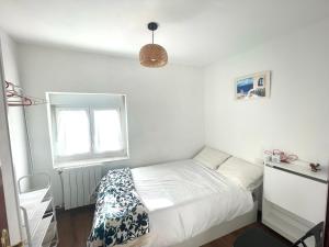 a white bedroom with a bed and a window at La Atalaya in Laredo