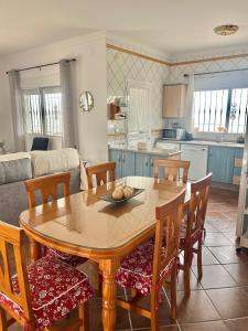 kuchnia i salon z drewnianym stołem i krzesłami w obiekcie Casa rural Villa Miradri w mieście Torrox
