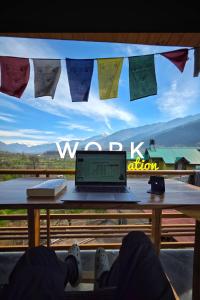 a person sitting in front of a table with a laptop at Zankhrpas A Himalayan Home - Manali in Manāli