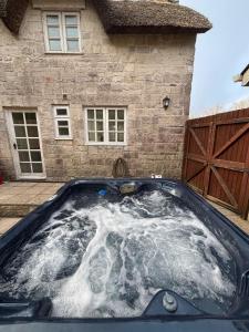 an outdoor hot tub in front of a house at Lupin Cottage Hot Tub Hide Out Dog Friendly in Weymouth