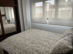 a bedroom with a bed and a window and a mirror at Ático Jovellanos in Gijón