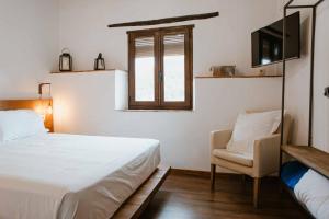 a bedroom with a bed and a chair and a window at Casa Rural Las Tinajas de Naya in Alcalá del Júcar