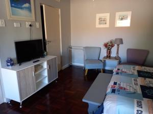 a hotel room with a bed and a tv and a bedroom at Sunshine Cottage in Fish Hoek