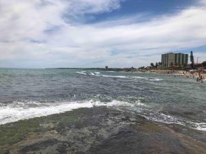 a beach with people in the water and a building at Vila dos ventos in Marataizes